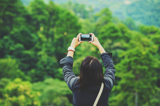 asian woman taking photo mountain view by phone