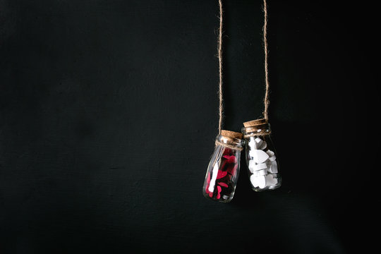 Two bottles full of white and red decorative hearts over black background. St Valentine concept. Copy space