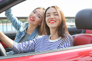 Two beautiful young women in cabriolet outdoors