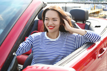 Beautiful young woman in cabriolet outdoors