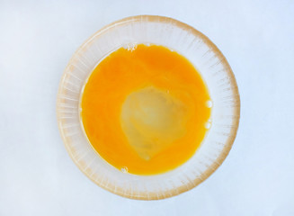 Egg yolk and white in a bowl on white background.