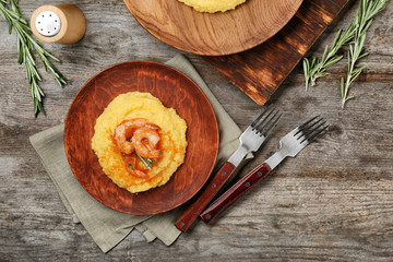 Plate with fresh tasty shrimp and grits on wooden table, top view