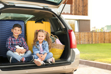 Cute children sitting in car trunk, outdoors