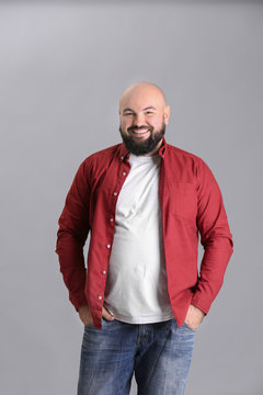 Overweight young man in red shirt on light background