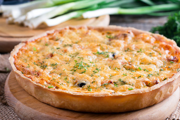 French onion cheese quiche or pie sprinkled with parsley on wooden table. Horizontal