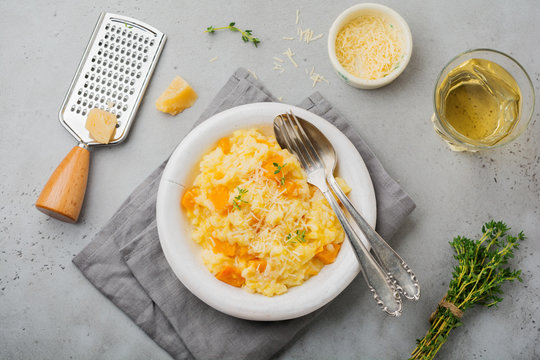 Pumpkin risotto with thyme, garlic, parmesan cheese and white wine on gray concrete or stone  background. Selective focus. Rustic style. Top view.