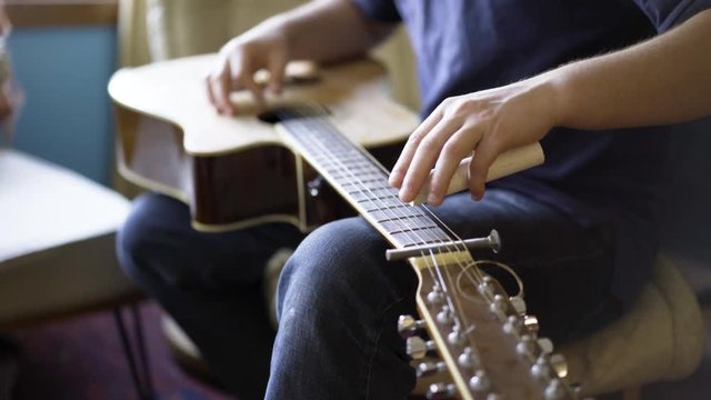 Shallow depth of field with focus on slider of six string slide guitar.