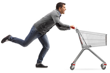 Guy running and pushing an empty shopping cart isolated on white background