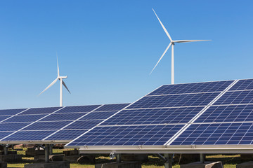solar cells with wind turbines generating electricity in hybrid power plant systems station on blue sky background alternative renewable energy from nature  Ecology concept.    - 182846082