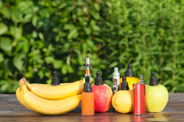 Electronic cigarette. Liquid and fruits on a wooden table.