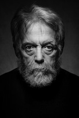 Portrait of a characteristic senior man with gray hair and beard, he looks into the camera