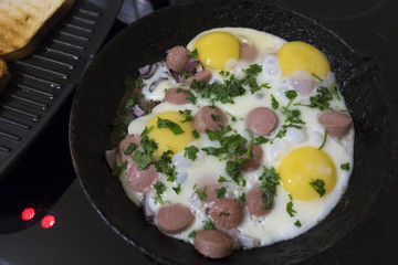 cooking fried eggs with sausages