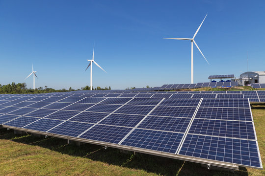 Solar panels and wind turbines generating electricity is solar energy and wind energy in hybrid power plant systems station use renewable energy to generate electricity with blue sky background 