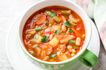 Italian minestrone soup in bowl on gray stone background