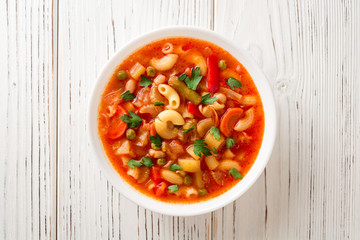 Italian minestrone soup on white wooden background.