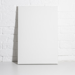 Mock up poster in white interior. Empty blank canvas leaning against a brick wall. Poster template.