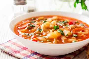 Italian minestrone soup on white wooden background.