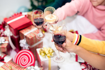 Hands of people celebrating New year party in home with wine drinking glasses. New year and Christmas party concept. Happiness and Friendship concept. Relation and Funny together theme. Clinking glass