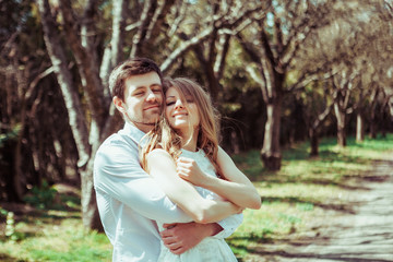 Naklejka premium Beautiful couple in love on a walk in summer forest. Hugging and looking to camera