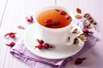 Cup of herbal tea from rose hips on purple wooden background
