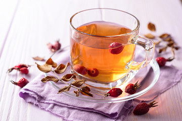 Cup of herbal tea from rose hips on purple wooden background