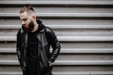 Modern young bearded man in black style clothes standing in around urban background. - Powered by Adobe