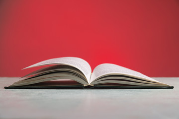 Composition with vintage old hardback books, diary, fanned pages on wooden deck table and red background. Books stacking. Back to school. Copy Space. Education background.