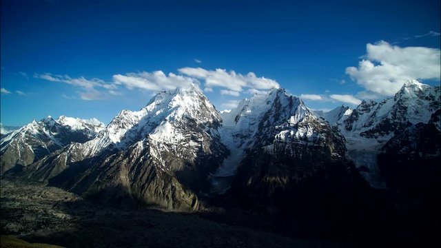 Quickly running white clouds in the blue sky over the high snowy mountains in Karakorum Pakistan