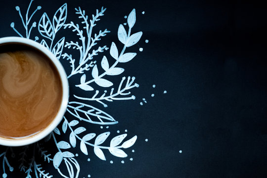 piece of cake and a cup of coffee on a black background decorated painted white snowflake.
