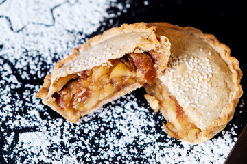 Apple pie delicious tart with nuts and on a black background and ingredients of which in turn it is cooked. Close up.