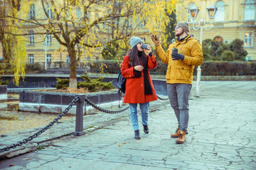 man flirting with woman while walking the park with cup of coffee