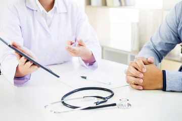 patient listening intently to a male doctor explaining patient symptoms or asking a question as they discuss paperwork together in a consultation