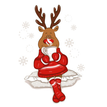 Christmas reindeer sits on a pillow. It's holds a mug with hot tea in his hands. From the mug there is steam. It's is wearing a warm knitted sweater and socks with ornament. Isolated. 