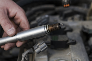 The hand holds the spark plug.