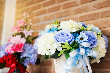 Artificial flower in the pot over wood table , brick wall background
