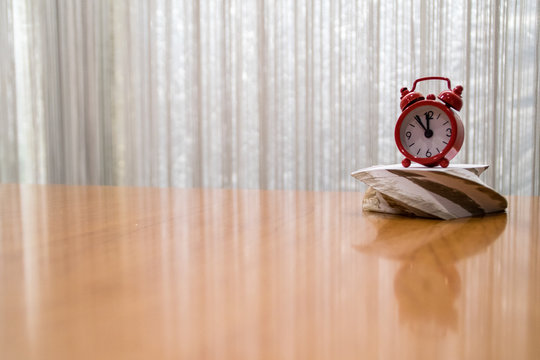 on the right side of the empty table red clock and block of paper