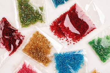 Different colour beads for handcraft and beading in plastic packages on a white background