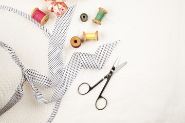 Set of tools and accessories for sewing and needlework with threads in spools, needles, measuring tape and other items on a white background, top view