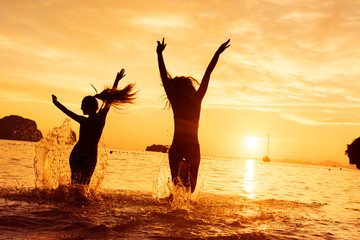 Two happy girls runs to sunset sea