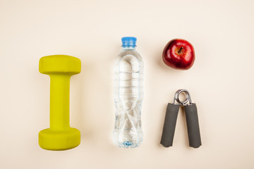 Sports equipment with bottle of water and red apples top view