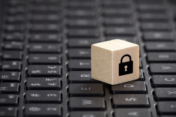 Wooden block with lock graphic on laptop keyboard. Computer security concept. 