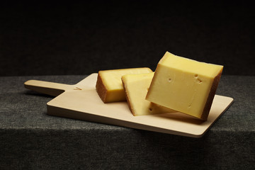 Vorarlberger Bergkäse auf einem Holzbrett auf dunklem Hintergrund