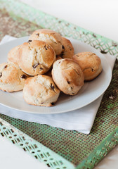 Frische, selbstgebackene Buttermilch-Scones mit Rosinen auf weißem Teller, darunter eine Stoffserviette und ein altes, rostiges Metalltablett