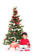Portrait of cute mixed race little boy sitting on floor near Christmas tree with gift box in his hands
