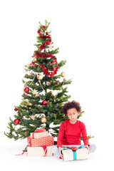 Portrait of cute mixed race little boy sitting on floor near Christmas tree with gift box in his hands