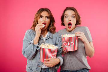 Shocked women friends eating popcorn watch film.