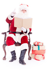 Portrait of santa Claus sitting in chair and reading a book on white background