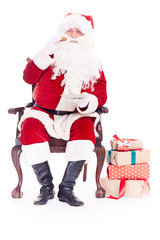 Portrait of Santa Claus sitting in chair and eating cookies isolated on white