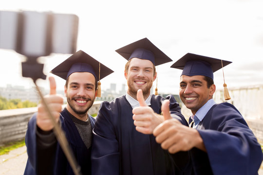 happy male students or graduates taking selfie