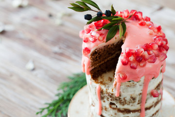 Festive honey cake with pomegranate seeds on wooden background